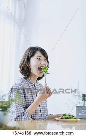 Stock Photo - Young Japanese woman eating salad. Fotosearch