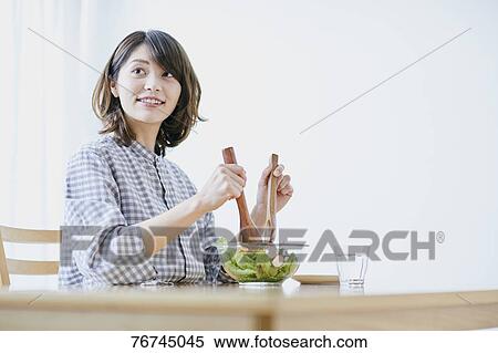 Stock Photography - Young Japanese woman eating salad. Fotosearch