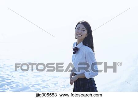 Stock Image - Young Japanese woman in a high school uniform by the sea, Chiba, Japan. Fotosearch