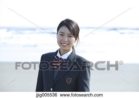 Stock Photograph - Young Japanese woman in a high school uniform by the sea, Chiba, Japan. Fotosearch