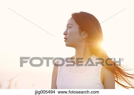 Young Japanese woman in a white dress at a cliff over the sea at sunrise, Chiba, Japan View Large Photo Image Picture - Young Japanese woman in a white dress at a cliff over the sea at sunrise, Chiba, Japan. Fotosearch