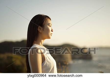 Young Japanese woman in a white dress at a cliff over the sea at sunrise, Chiba, Japan View Large Photo Image Picture - Young Japanese woman in a white dress at a cliff over the sea at sunrise, Chiba, Japan. Fotosearch