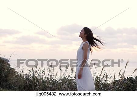 Young Japanese woman in a white dress at a cliff over the sea at sunrise, Chiba, Japan View Large Photo Image Stock Image - Young Japanese woman in a white dress at a cliff over the sea at sunrise, Chiba, Japan. Fotosearch