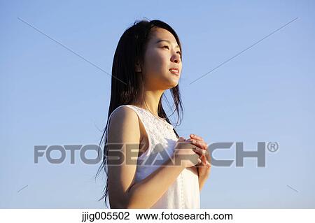 Young Japanese woman in a white dress at a cliff over the sea at sunrise, Chiba, Japan View Large Photo Image Stock Image - Young Japanese woman in a white dress at a cliff over the sea at sunrise, Chiba, Japan. Fotosearch