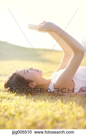 Stock Image - Young Japanese woman in a white dress at a cliff over the sea at sunrise, Chiba, Japan. Fotosearch