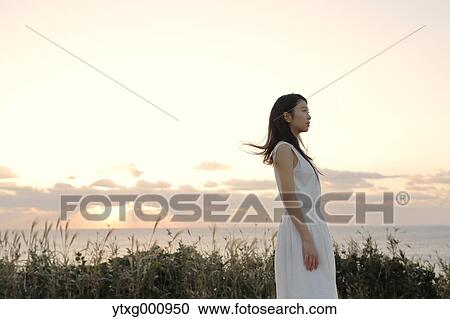 Young Japanese woman in a white dress at a cliff over the sea at sunrise, Chiba, Japan View Large Photo Image Stock Image - Young Japanese woman in a white dress at a cliff over the sea at sunrise, Chiba, Japan. Fotosearch