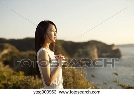 Young Japanese woman in a white dress at a cliff over the sea at sunrise, Chiba, Japan View Large Photo Image Stock Image - Young Japanese woman in a white dress at a cliff over the sea at sunrise, Chiba, Japan. Fotosearch