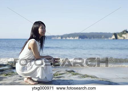 Stock Image - Young Japanese woman in a white dress by the sea, Chiba, Japan. Fotosearch