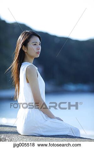 Stock Photo - Young Japanese woman in a white dress by the sea, Chiba, Japan. Fotosearch