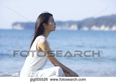 Stock Photograph - Young Japanese woman in a white dress by the sea, Chiba, Japan. Fotosearch
