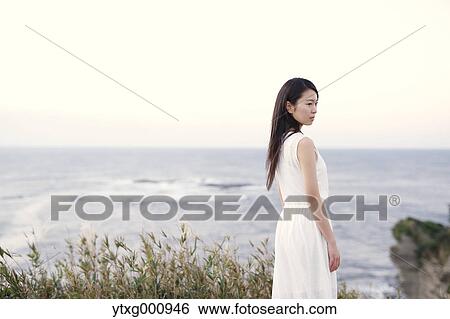 Young Japanese woman in a white dress at a cliff over the sea at sunrise, Chiba, Japan View Large Photo Image Stock Photograph - Young Japanese woman in a white dress at a cliff over the sea at sunrise, Chiba, Japan. Fotosearch