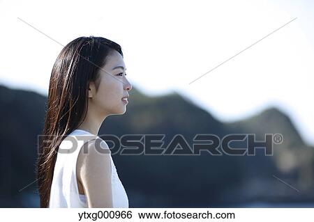 Stock Photograph - Young Japanese woman in a white dress by the sea, Chiba, Japan. Fotosearch