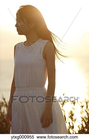 Young Japanese woman in a white dress at a cliff over the sea at sunrise, Chiba, Japan View Large Photo Image Stock Photography - Young Japanese woman in a white dress at a cliff over the sea at sunrise, Chiba, Japan. Fotosearch