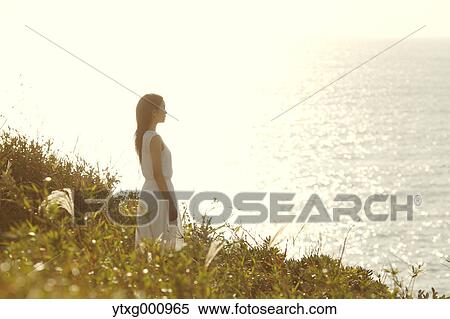 Young Japanese woman in a white dress at a cliff over the sea at sunrise, Chiba, Japan View Large Photo Image Stock Photography - Young Japanese woman in a white dress at a cliff over the sea at sunrise, Chiba, Japan. Fotosearch