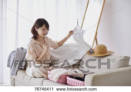 Stock Image - Young Japanese woman on sofa. Fotosearch