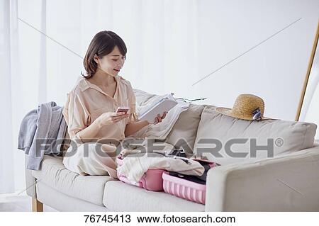 Stock Image - Young Japanese woman on sofa. Fotosearch
