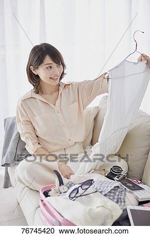 Stock Image - Young Japanese woman on sofa. Fotosearch