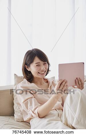 Stock Photo - Young Japanese woman on sofa. Fotosearch