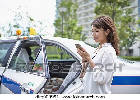 Stock Image - Young Japanese woman riding a taxi downtown Tokyo, Japan. Fotosearch
