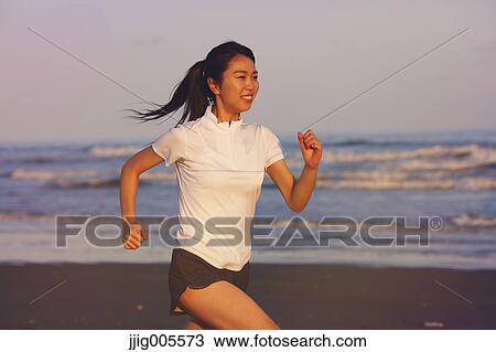 Stock Image - Young Japanese woman training on the beach. Fotosearch