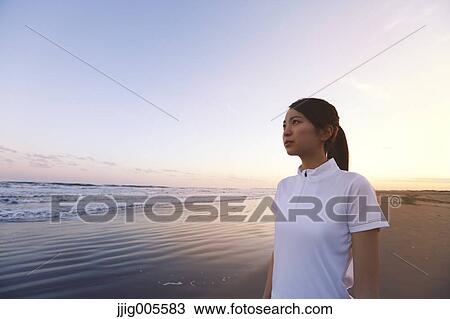 Stock Image - Young Japanese woman training on the beach. Fotosearch