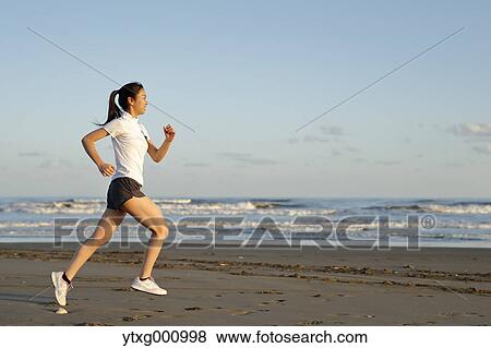 Stock Photo - Young Japanese woman training on the beach. Fotosearch