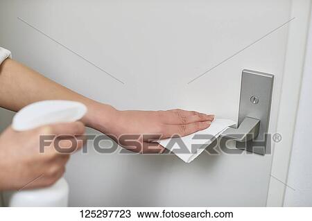 Stock Image - Japan man disinfecting door knob with alcohol. Fotosearch