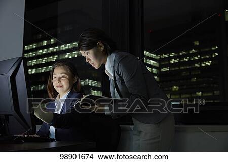 Picture - Japanese business people working late at night. Fotosearch