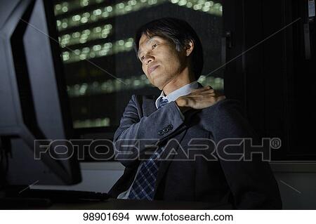 Picture - Japanese businessman working late at night. Fotosearch