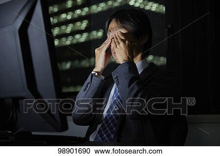 Stock Image - Japanese businessman working late at night. Fotosearch