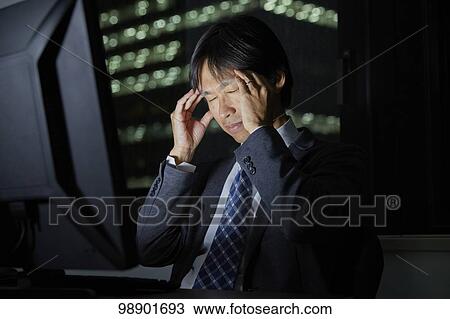 Stock Image - Japanese businessman working late at night. Fotosearch