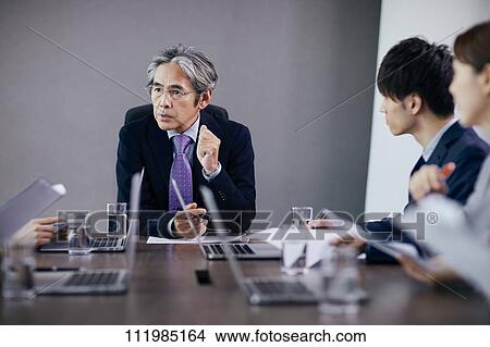 Picture - Japanese businesspeople having a meeting. Fotosearch