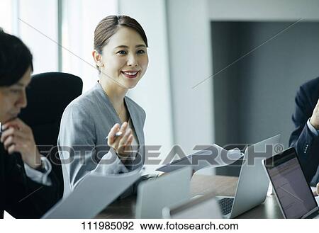 Stock Image - Japanese businesspeople having a meeting. Fotosearch