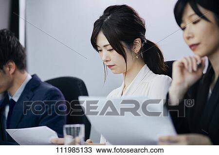Stock Image - Japanese businesspeople having a meeting. Fotosearch
