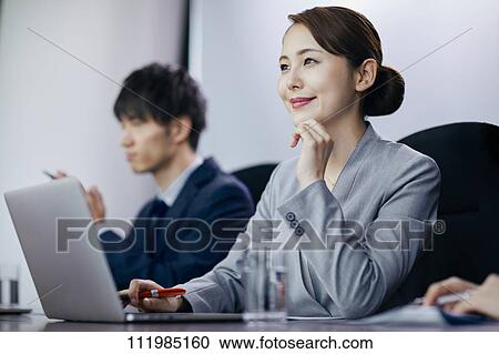 Stock Image - Japanese businesspeople having a meeting. Fotosearch