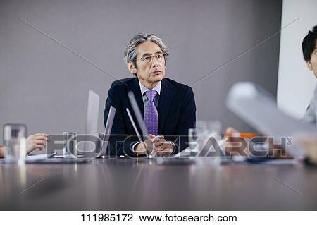 Stock Image - Japanese businesspeople having a meeting. Fotosearch