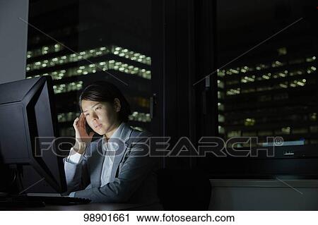 Stock Image - Japanese businesswoman working late at night. Fotosearch