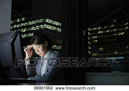 Stock Image - Japanese businesswoman working late at night. Fotosearch