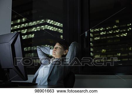 Stock Image - Japanese businesswoman working late at night. Fotosearch