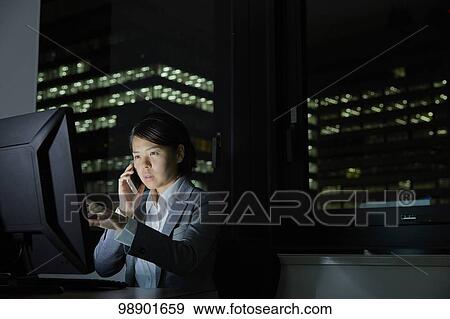 Stock Photo - Japanese businesswoman working late at night. Fotosearch