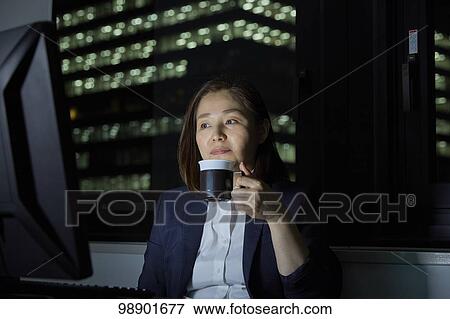 Stock Photo - Japanese businesswoman working late at night. Fotosearch