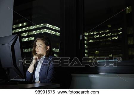 Stock Photograph - Japanese businesswoman working late at night. Fotosearch