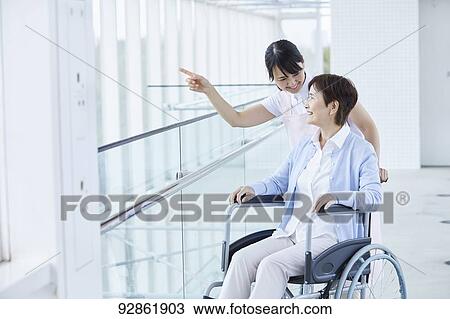 Stock Image - Japanese caretaker helping senior patient. Fotosearch