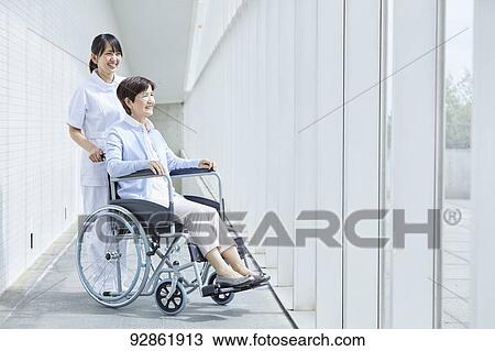 Stock Image - Japanese caretaker helping senior patient. Fotosearch