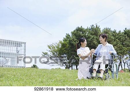 Stock Photo - Japanese caretaker helping senior patient. Fotosearch