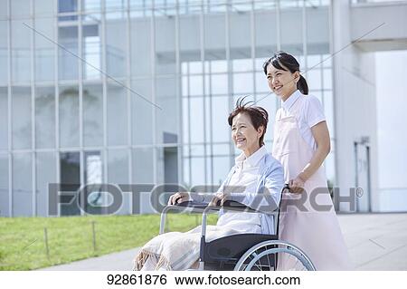 Stock Photograph - Japanese caretaker helping senior patient. Fotosearch