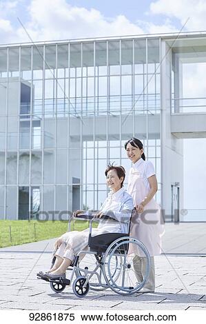 Stock Photography - Japanese caretaker helping senior patient. Fotosearch