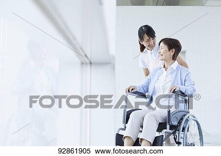 Stock Photography - Japanese caretaker helping senior patient. Fotosearch