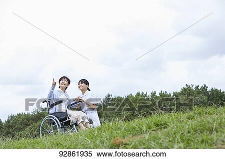 Stock Photography - Japanese caretaker helping senior patient. Fotosearch