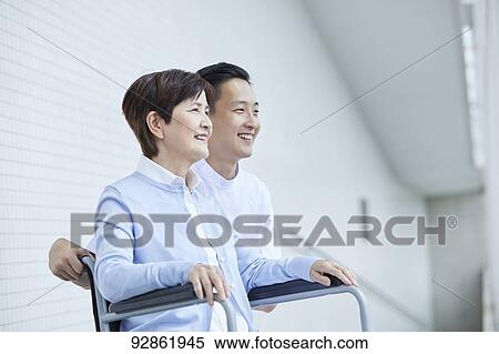 Stock Photography - Japanese caretaker helping senior patient. Fotosearch